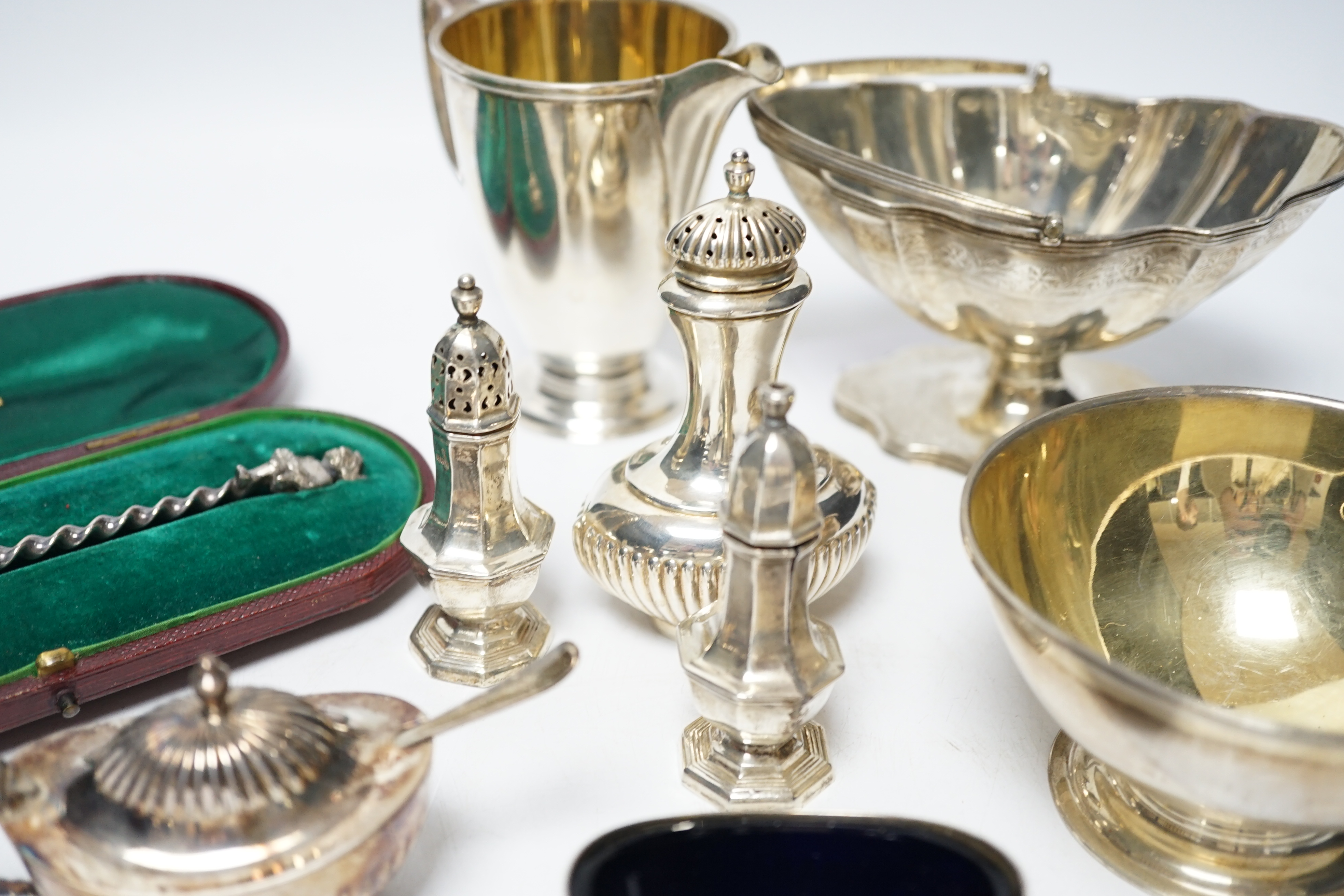 A group of small silver including Edwardian silver oval sugar basket, a modern silver cream jug and sugar bowl, five assorted condiments, a silver sifter spoon and a late Victorian scent bottle, 56mm.
